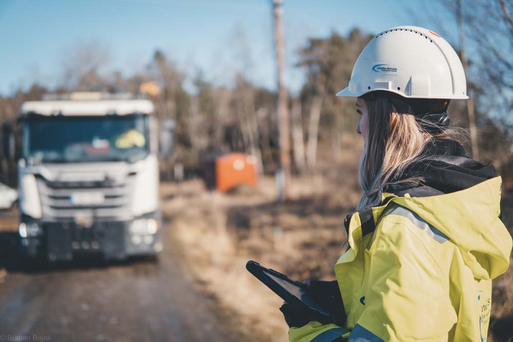 En kvinnlig kollega står med en surfplatta framför en lastbil