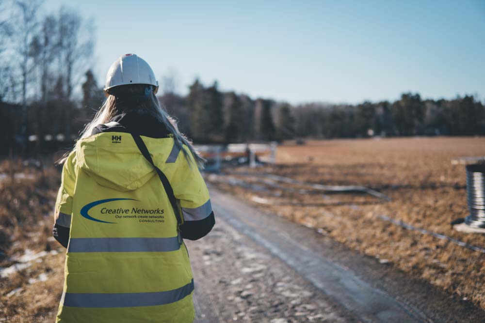 En kvinna i gul jacka från Creative Networks går på en landsväg